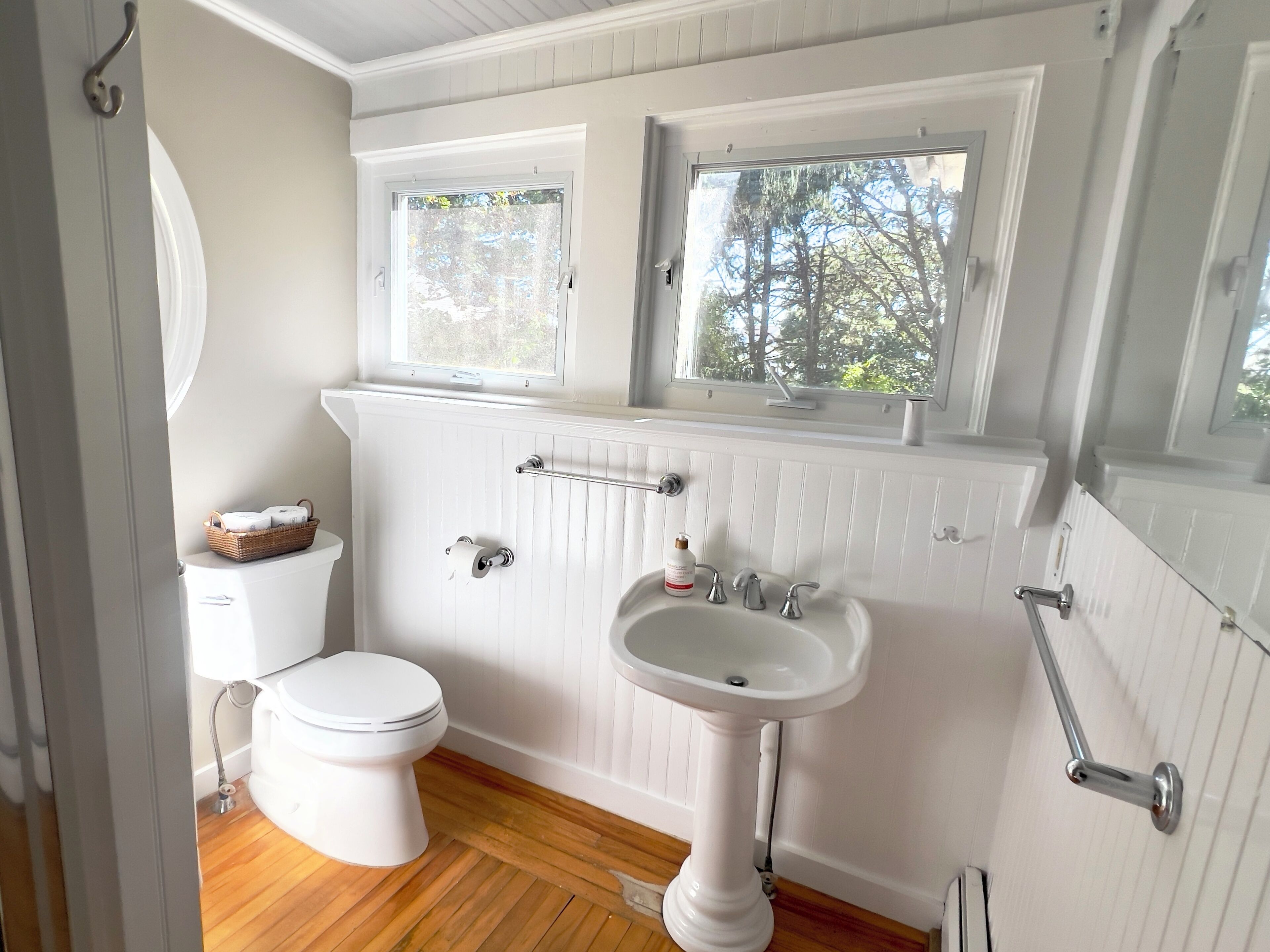 A bathroom with a toilet, sink, and window.