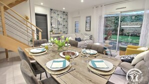Un comedor moderno con una mesa de madera dispuesta para cuatro personas, rodeado de sofás y una escalera.