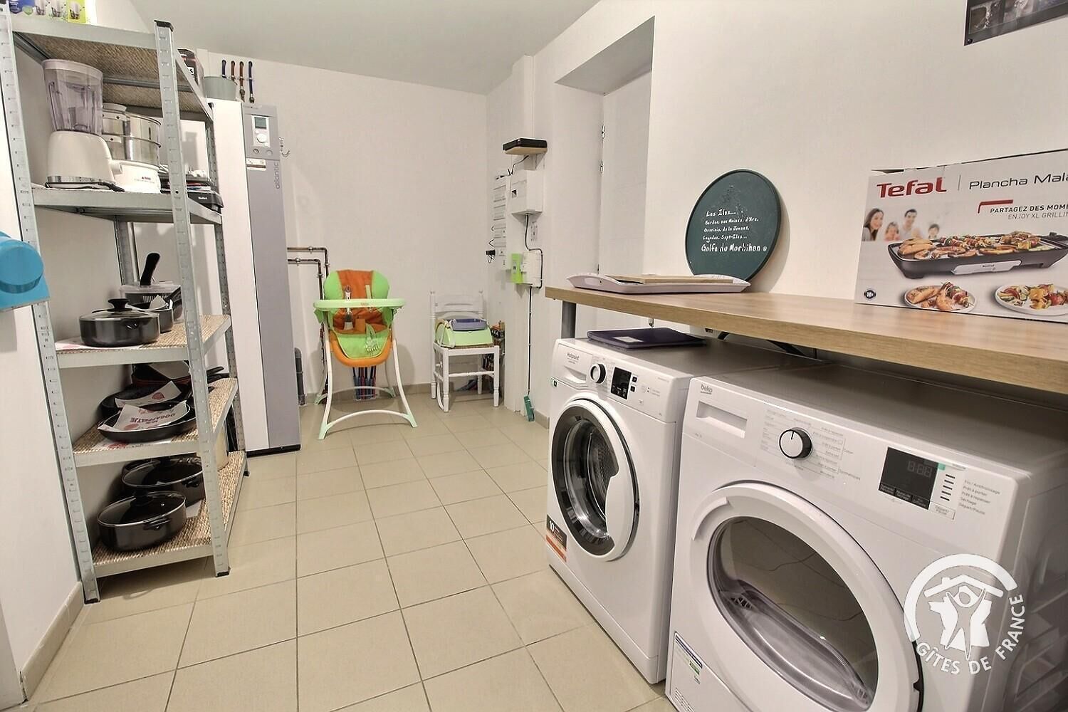 Uma lavanderia equipada com máquina de lavar, secadora e uma prateleira com utensílios de cozinha.