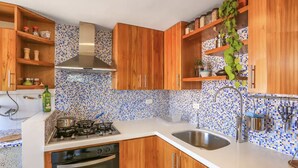 A kitchen with wooden cabinets, a gas stove, a dishwasher, and a sink. - Airy Penthouse with Private Rooftop Terrace in a Quaint Colombian Neighbourhood (Envigado)