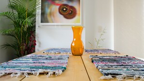 A wooden table with woven placemats, a vase, and a painting of an eye on the wall. - Airy Penthouse with Private Rooftop Terrace in a Quaint Colombian Neighbourhood (Envigado)