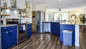 A modern kitchen with blue cabinets, stainless steel appliances, and wooden flooring. - Spacious 4 Bed, Central AC, Fire Pit, Grill, Games (Colorado Springs)