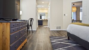A modern bedroom with a large bed, a dresser, a television, and a chair. - Spacious 4 Bed, Central AC, Fire Pit, Grill, Games (Colorado Springs)