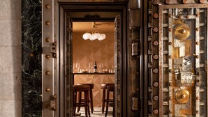 A luxurious bar area with marble flooring, a bar counter, and three wooden stools. - The Liberty Trust (Roanoke)