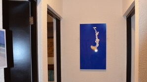 Un pasillo con un mapa azul en la pared, una puerta a la izquierda y una habitación parcialmente visible con una cama a la derecha.