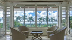 A room with large windows, two beige chairs, and a small table.