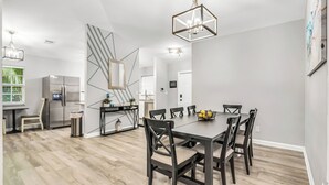 Una cuina moderna amb frigorífic integrat, una taula de dinar amb cadires i una escala que mena a un altre nivell.