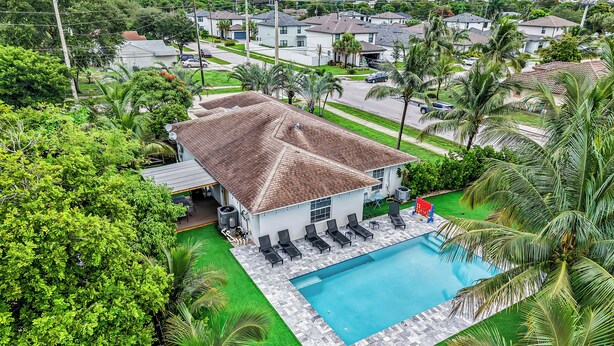 Un edifici residencial amb piscina, envoltat de vegetació exuberant i palmeres.