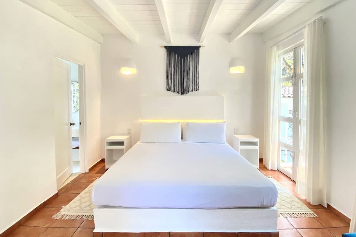 Un'ampia camera da letto con un letto grande, pareti bianche e soffitto a falde.