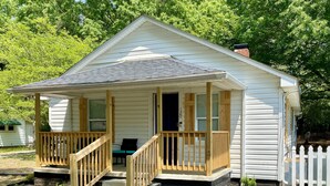 A small, single-story cabin with a porch and a front door. - Quaint 2 bed 1 bath cottage style home (Kernersville)