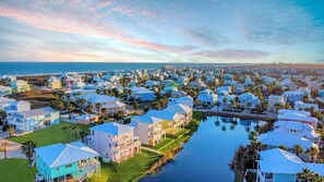 A coastal residential area with houses along a waterway, featuring a mix of single and multi-story buildings, some with balconies.