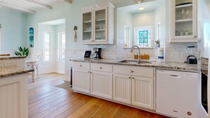 A spacious kitchen with white cabinetry, a dishwasher, and a countertop with various appliances.