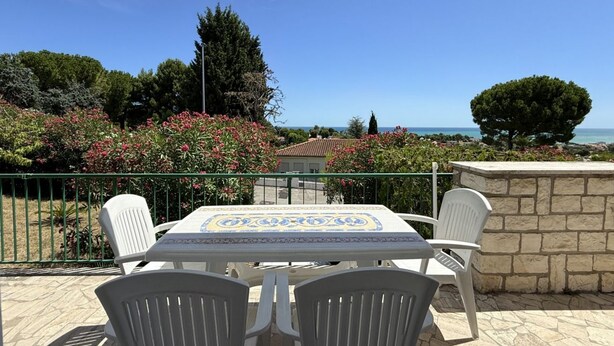 A patio with a table and chairs, overlooking a coastal view with trees and a building. - N122 - Numana, delightful single villa with garden (Numana)