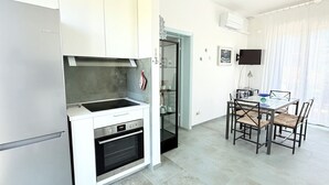 A modern kitchen with white cabinets, a built-in oven, and a dining area with a table and chairs. - N122 - Numana, delightful single villa with garden (Numana)