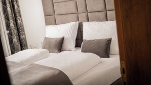 A double bed with a tufted headboard, two pillows, and a bedside table with a lamp. - Exclusive apartment with mountain views in a ski paradise (Mauterndorf)