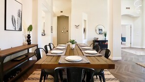 A dining area with a wooden table set for six, surrounded by black chairs.