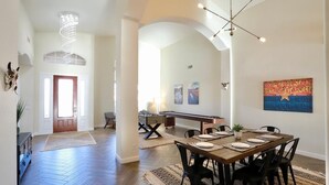 A spacious dining area with a long wooden table set for six, surrounded by black chairs.