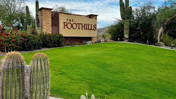 The Foothills hotel with a well-maintained lawn, cacti, and a clear sky.
