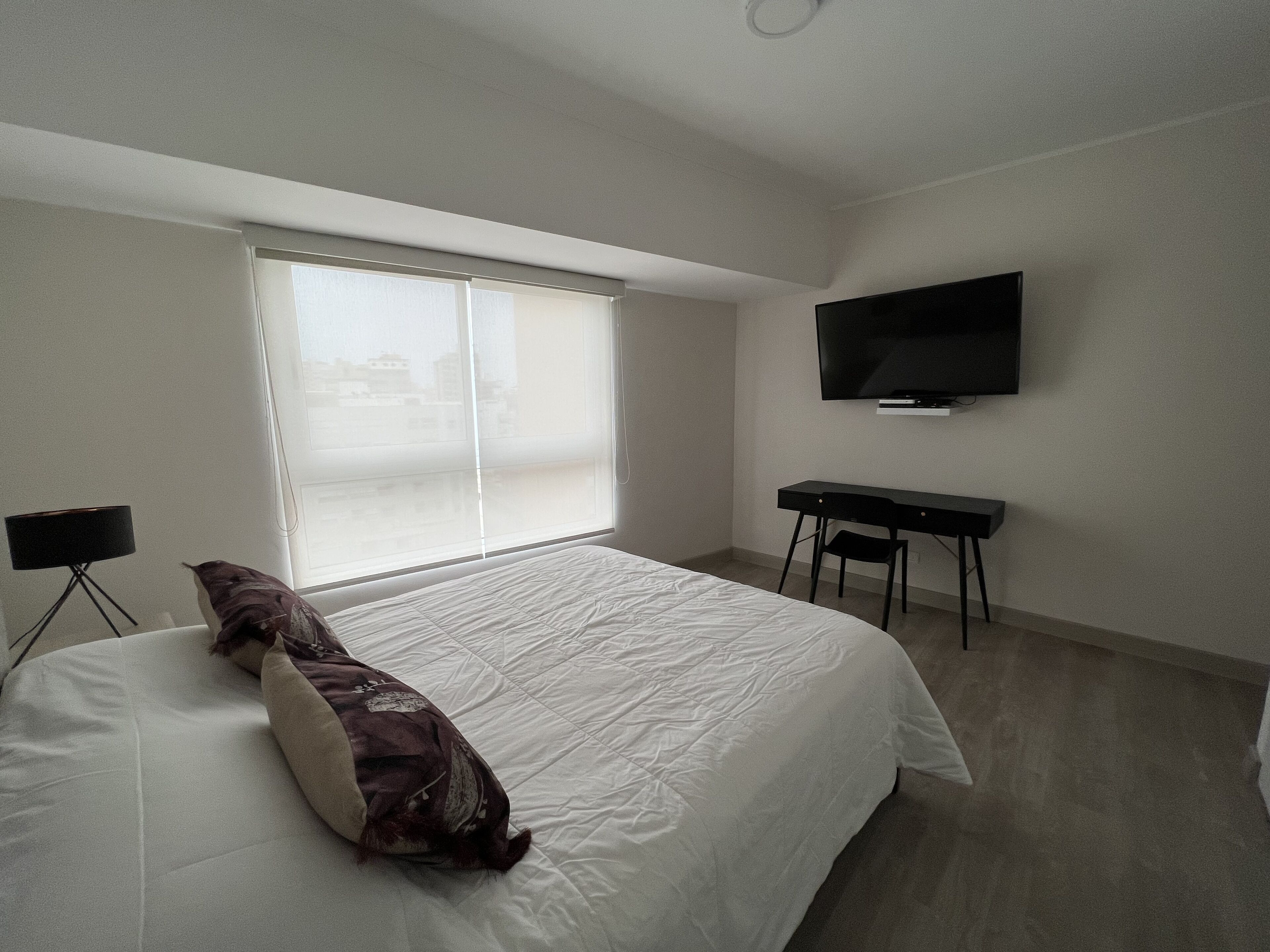 Un dormitorio con cama, escritorio, silla y televisor.