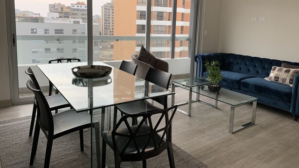 Un salon moderne avec un coin repas, de grandes fenêtres et une vue sur la ville.