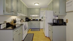 A compact kitchen with light-colored cabinets, a stove, a microwave, and a refrigerator. - Bee Humble Cottage w/in 20mins to Public Beaches (Gloucester)