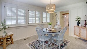 A dining area with a round table, four chairs, a hanging light fixture, and a window with blinds. - Bee Humble Cottage w/in 20mins to Public Beaches (Gloucester)