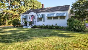 A single-story house with a front porch, a flag, and a well-maintained lawn. - Bee Humble Cottage w/in 20mins to Public Beaches (Gloucester)