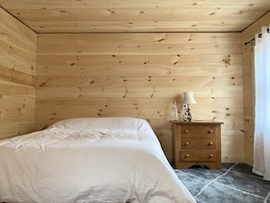 A wooden-paneled room with a bed, a nightstand with a lamp, and a window with curtains. - Stream House (The Lorca, Catskills) - 10 min to Belleayre, 25 min to Windham (Shandaken)