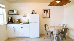A compact kitchen with a refrigerator, microwave, and a dining area with a table and chairs.