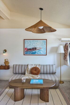 A living room with a sofa, a coffee table, a hanging light fixture, a framed picture, and a floor lamp.
