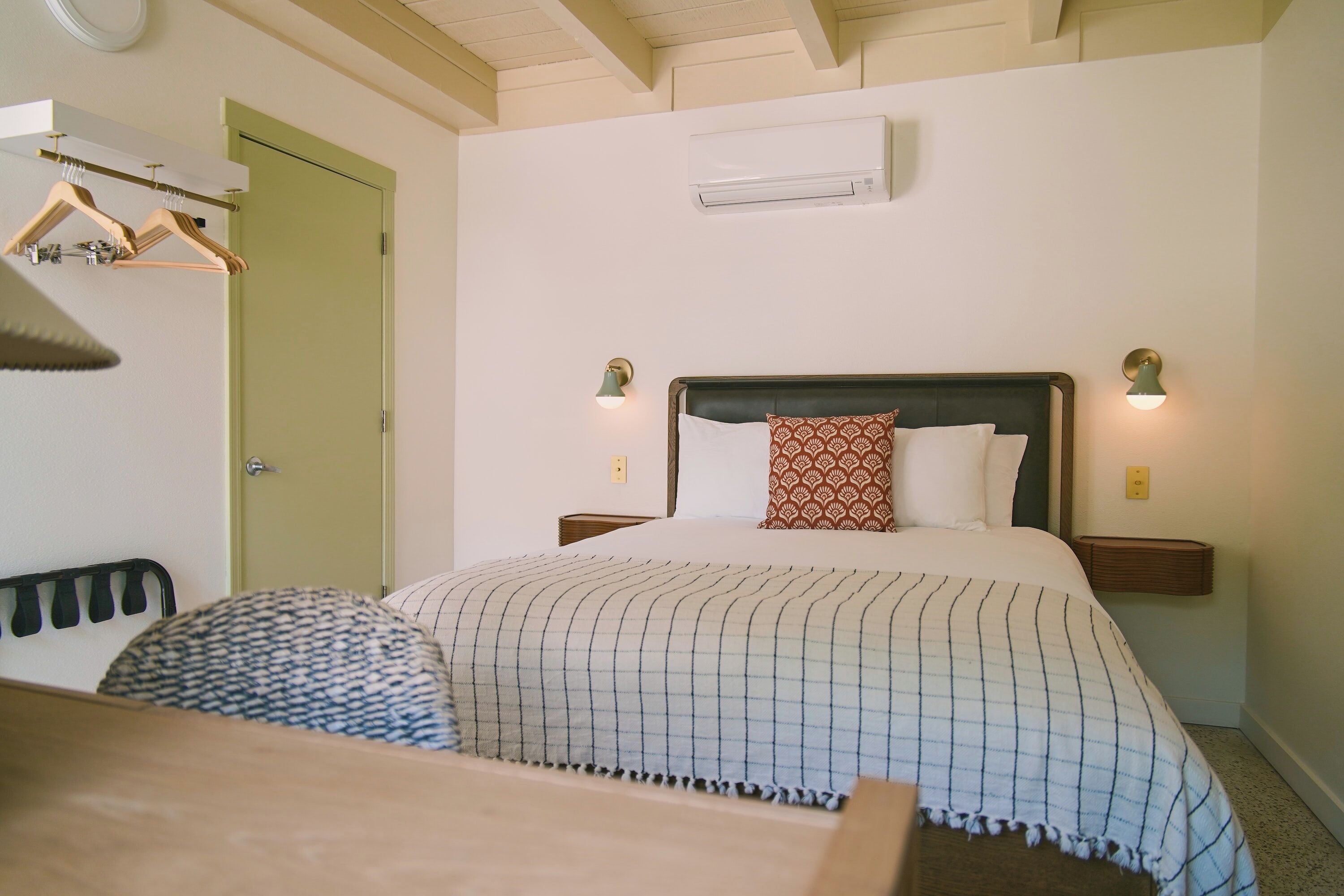 Ein Hotelzimmer mit Bett, Nachttischen, einem Kleiderschrank und einer Klimaanlage.
