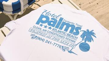 A beach chair with a white and blue striped cushion and a white towel with text advertising a hotel.