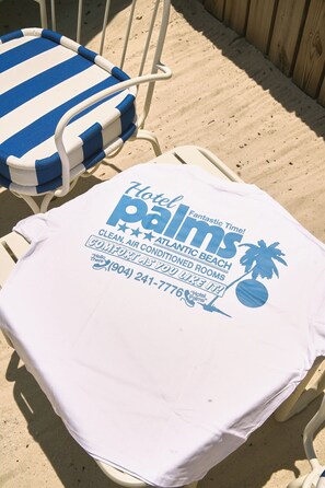Une chaise de plage avec un coussin rayé bleu et blanc et une serviette blanche sur laquelle est imprimée une publicité pour un hôtel.