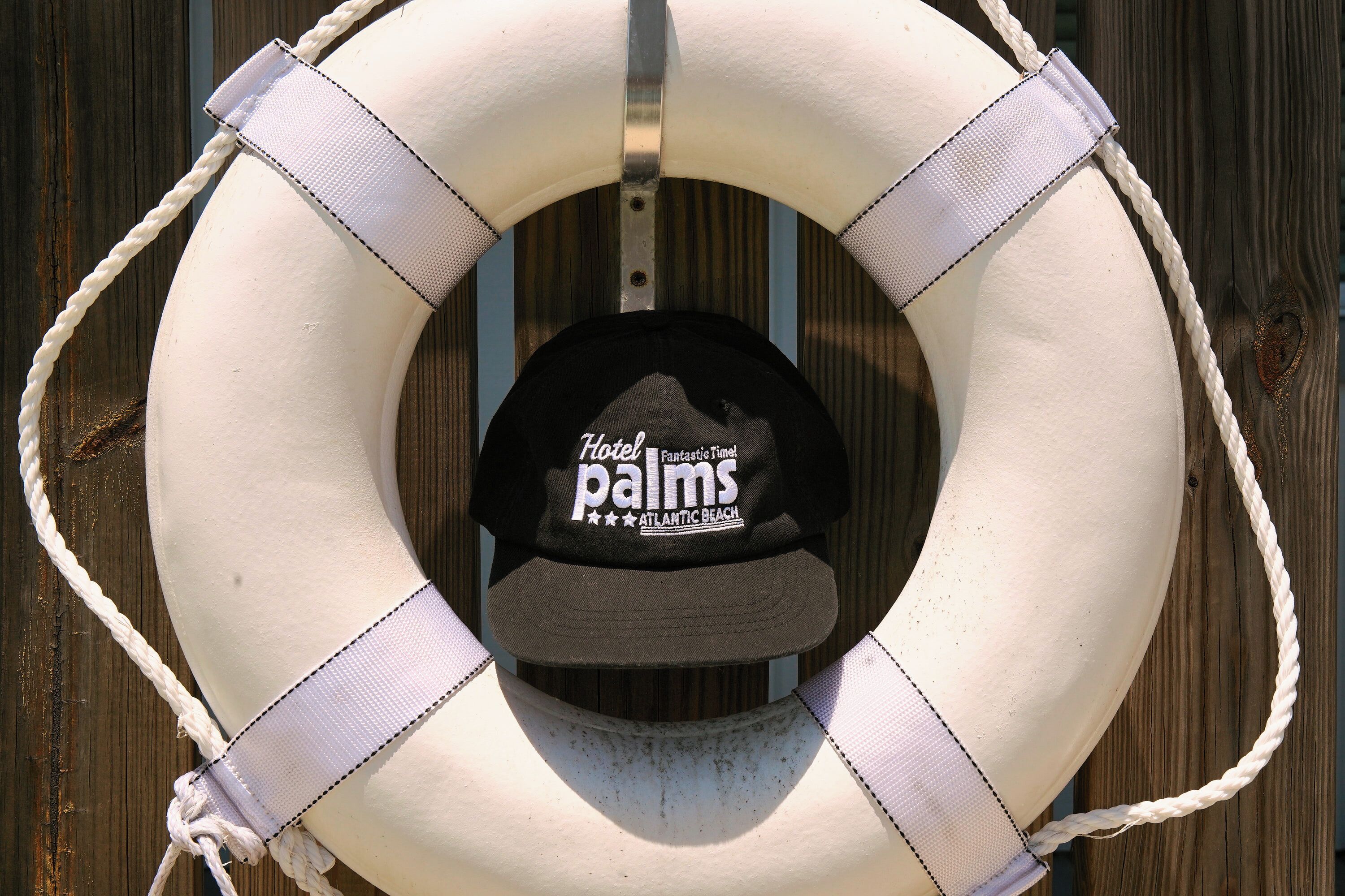 A lifebuoy with a black cap featuring 'Hotel Palm's Fantastic Time Atlantic Beach' text.