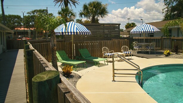 A backyard with a swimming pool, wooden deck, and outdoor furniture. - Hotel Palms (Atlantic Beach)