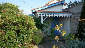 A house with a blue door, a small porch, and a garden with various plants and flowers. - Ref 541 - Quiet house close to the beaches and the city center (SOULAC SUR MER)