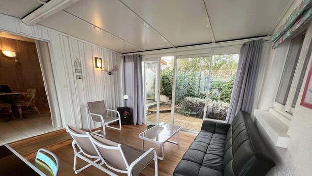 A modern living room with a black leather sofa, white armchairs, and a glass coffee table. - Ref 541 - Quiet house close to the beaches and the city center (SOULAC SUR MER)