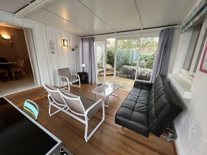 A modern living room with a black leather sofa, white armchairs, and a glass coffee table. - Ref 541 - Quiet house close to the beaches and the city center (SOULAC SUR MER)