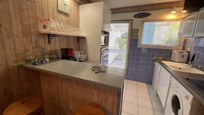 A compact kitchen with wooden paneling, a built-in microwave, a coffee maker, and a washing machine. - Ref 541 - Quiet house close to the beaches and the city center (SOULAC SUR MER)