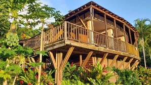 A wooden structure with a balcony, surrounded by tropical vegetation. - Hacienda Elena Paraiso Tropical (Canóvanas)