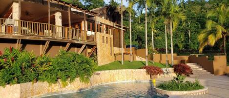 A resort with a pool, wooden balconies, and tropical landscaping.