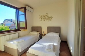 Ein Schlafzimmer mit zwei Betten, einem Fenster und einer Wanddekoration.