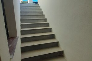 A staircase with a plain wall and a window at the top.