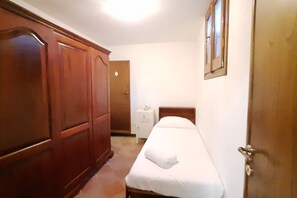 Ein Schlafzimmer mit Bett, Schrank, Nachttisch und Tür.