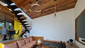 Un intérieur moderne avec un escalier en bois, un canapé, un bureau et une grande fenêtre.