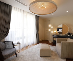 A modern hotel room with a large round mirror, a round ceiling light, a sofa, an ottoman, and a small table with a cup and saucer. - Ecole St Pierre Hotel (Istanbul)