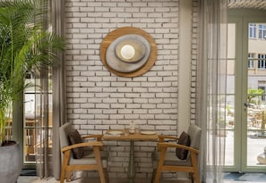 Un coin repas avec un mur en briques, une table ronde en bois et deux chaises.