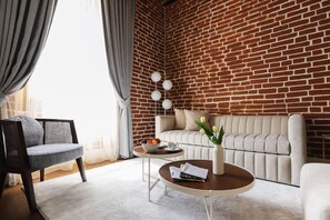 A modern living room with a brick wall, a sofa, a coffee table, and a chair.
