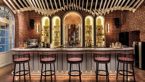 A bar with a brick wall, wooden ceiling, and multiple stools. - Ecole St Pierre Hotel (Istanbul)