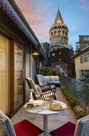 A terrace with outdoor seating, a dining table with plates of food, and a view of a historic tower in the background. - Ecole St Pierre Hotel (Istanbul)
